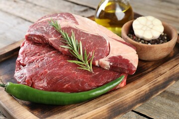 Fresh raw beef cut with spices on wooden table, closeup