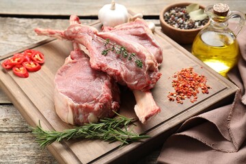 Fresh tomahawk beef cuts and spices on wooden table, closeup