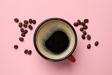 Fresh coffee in cup and roasted beans on pink background, top view