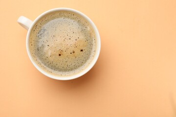 Fresh coffee in cup on beige background, top view. Space for text