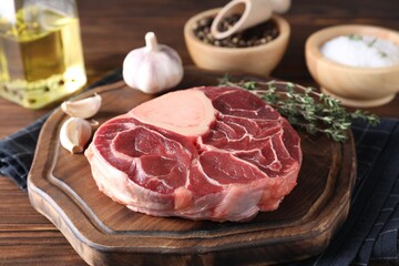 Piece of raw beef meat, garlic and thyme on wooden table, closeup