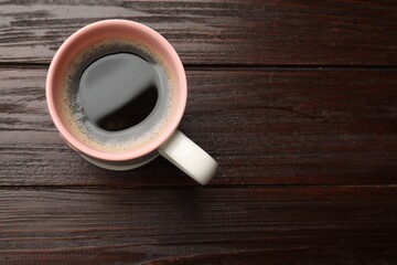 Cup of aromatic coffee on wooden table, top view. Space for text