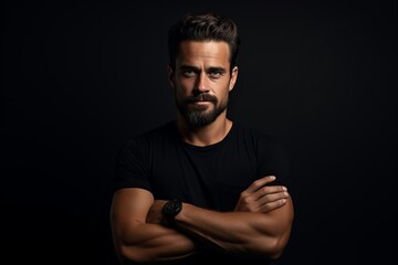 Handsome bearded man in black t-shirt with crossed arms.