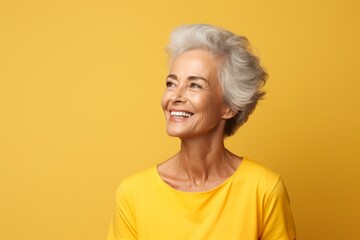 smiling senior woman in yellow t-shirt and glasses over yellow background