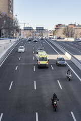 Road traffic at the exit of a tunnel on a highway exiting the city of Madrid with motorcycles and...