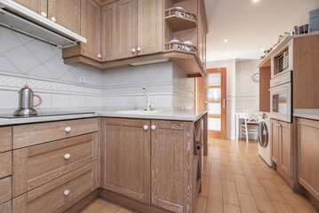 A kitchen with corner furniture in wood color with white grain and stoneware floors