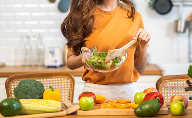 Portrait of beauty body slim healthy woman eating vegan food healthy with fresh vegetable salad in kitchen at home.diet, vegetarian, fruit, wellness, health, green food.Fitness and healthy food