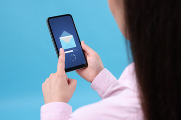 Got new message. Woman using smartphone on light blue background, closeup