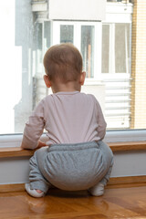 Baby looks out window, wants to play outside. Concept of wanting more fun
