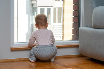 Baby waits by the window for dad to come home. Concept of family and longing