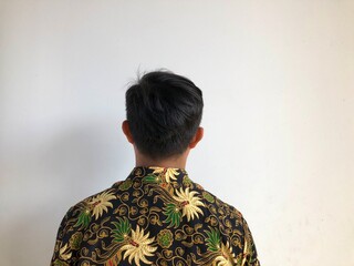 Asian man in batik shirt with his back facing the camera