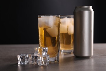 Energy drink in glasses, aluminium can and ice cubes on grey table
