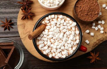 Tasty hot chocolate with marshmallows and ingredients on wooden table, flat lay