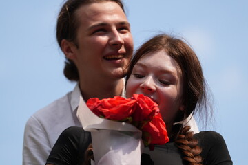 couple young man and woman hugging and holding the red bouquet rose flowers at outdoor space....