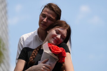couple young man and woman hugging and holding the red bouquet rose flowers at outdoor space....
