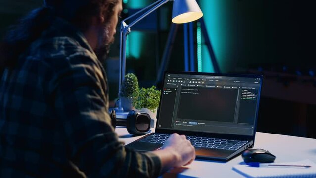 Skilled computer scientist writes code on laptop screen while in living room office using programming languages. Self employed IT specialist working on fixing database errors from home, camera A