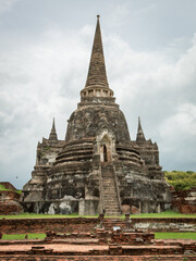 Fototapeta na wymiar Traditional Thai stone pagoda building structure and red brick ruins at Wat Phra Si Sanphet temple in Ayutthaya Thailand historical park on a cloudy day