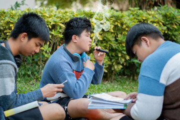 Asian preteen spending freetimes with friends, one of them reading a book and some of them smoking...