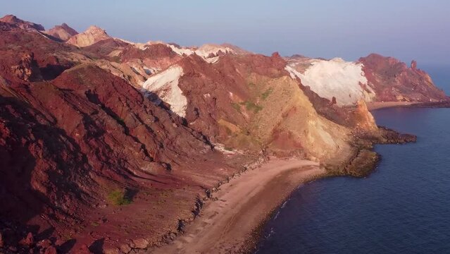 Coastal horizon mountain near the beach and blue color sea near the wind polished erosion mountain rocks in the golden sand beach in Iran Hormuz Island campsite the surfing water sport adventure