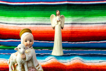 Baby Jesus and lamb figurine with Mexican blanket as backdrop.