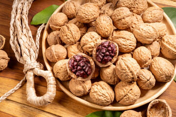 Red Walnuts in wooden bowl on wooden background, Walnuts kernels in wooden basket on wooden table.