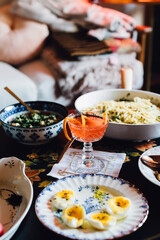coffee table spread with a variety of vegetarian dishes and cocktails: eggs, pasta, mushrooms, beans, radishes