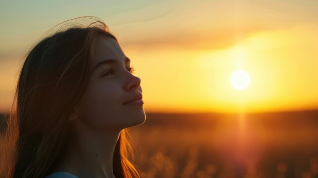 A teenage girl her eyes wide open and a small smile on her face as she gazes at a beautiful sunset and reflects on the beauty and vastness of the universe.