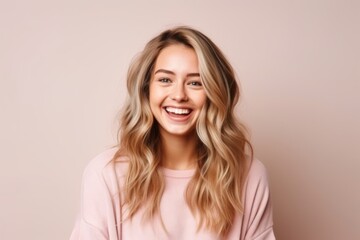 Portrait of a happy young woman with long blond hair over pink background