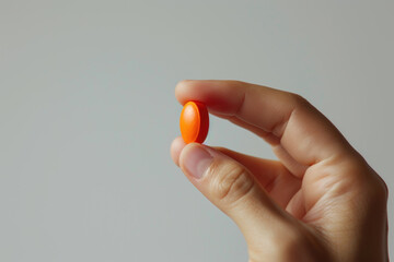 Hand holding orange pill, healthcare: medicine, antibiotic, supplement