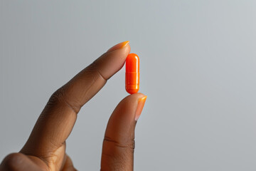 Hand holding orange pill, healthcare: medicine, antibiotic, supplement
