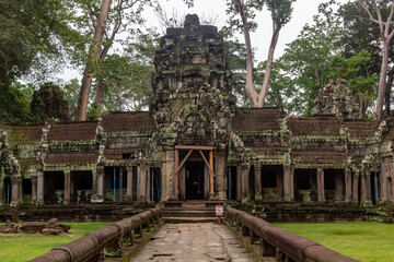 Moss covered stone beautiful temple ruin building architecture in Ta Prohm Tomb Raider entrance at Angkor Wat historical site in Seim Reap Cambodia on a cloudy overcast day