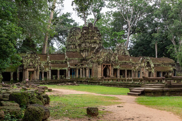 Fototapeta na wymiar Moss-covered green stone building structure exterior and bricks at Ta Prohm Tomb Raider temple complex in the lush green forest. Angkor Wat historical site, Siem Reap, Cambodia