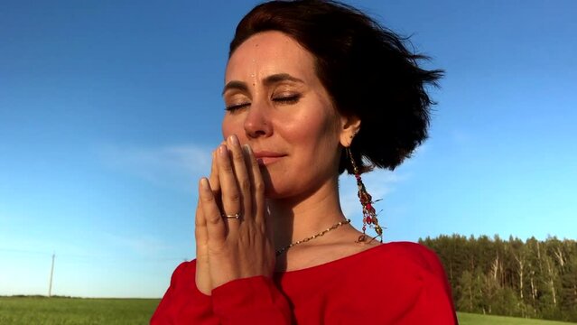 Believing woman with her eyes closed asking for forgiveness and peace. Stock clip. Feeling unity with nature.