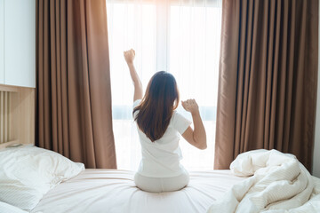 happy woman stretching on bed after wake up, young adult female rising arms and looking to window in the early morning. fresh relax and have a nice day concepts - Powered by Adobe