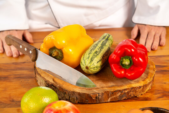  Variedade de vegetais coloridos na tábua de corte, ingredientes para uma vida saudavel e mão do chef ao fundo com a faca ao lado