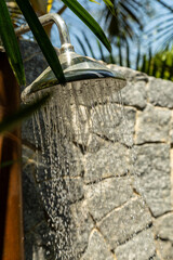 ducha refrescante ao ar livre, com parede de pedra e folhagem