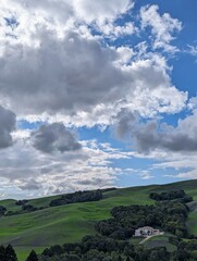 cozy house on green hills under a vast blue sky