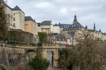 Fototapeta na wymiar Colorful pink, yellow, and grey buildings in the old town village along a walled cliff and old bridge of Luxembourg City Europe