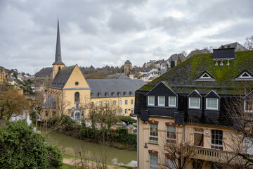 Church cathedral and colorful pink, yellow, and grey buildings in the old town village along a walled cliff and old bridge of Luxembourg City Europe