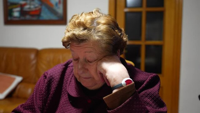 Close up portrait of old woman granny talking about health with SOS bracelet on