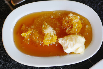 butter cream and honey in a bowl on table .