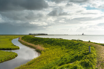 Dike along the shore of a lake under a stormy sky near Marken on the IJsselmeer in the Netherlands....