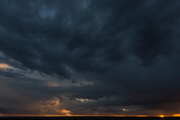 Landscape at sunset. A thunderstorm is approaching the village. Tragic gloomy sky. Panorama.