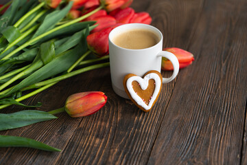 Fresh orange tulips and cappuccino mug with spring composition. Greeting card with copy space for Valentine's Day, Woman's Day and Mother's Day.
