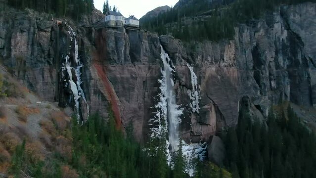 Bridal Veil Falls Telluride Colorado aerial drone frozen ice waterfall autumn sunset cool shaded Rocky Mountains Silverton Ouray Millon Dollar Highway historic town landscape slow right pan up reveal