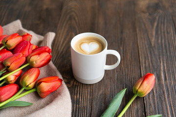 Fototapeta na wymiar Fresh orange tulips and cappuccino mug with spring composition. Greeting card with copy space for Valentine's Day, Woman's Day and Mother's Day.