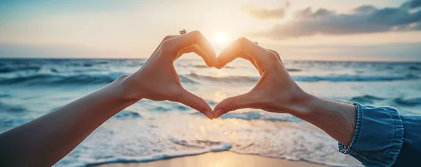 Foto op Canvas Two couple hands making heart symbol on sunset or sunrise beach background, love and compassion concept © Gethuk_Studio
