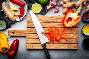 Food and cooking background. Wooden cutting board with chopped paprika and chef knife. Zucchini,...