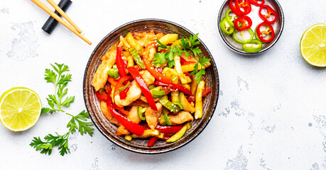 Stir fry turkey breast with red paprika and zucchini with sesame seeds, lime, garlic, ginger and soy sauce in ceramic bowl. White table background, top view