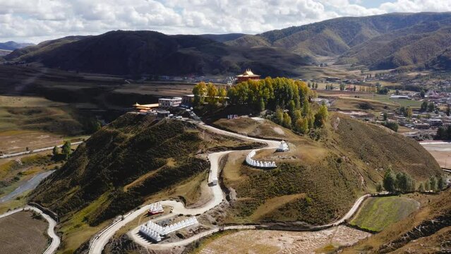 Aerial pullback establishes Sichuan Bamei temple on prominent hill with winding road